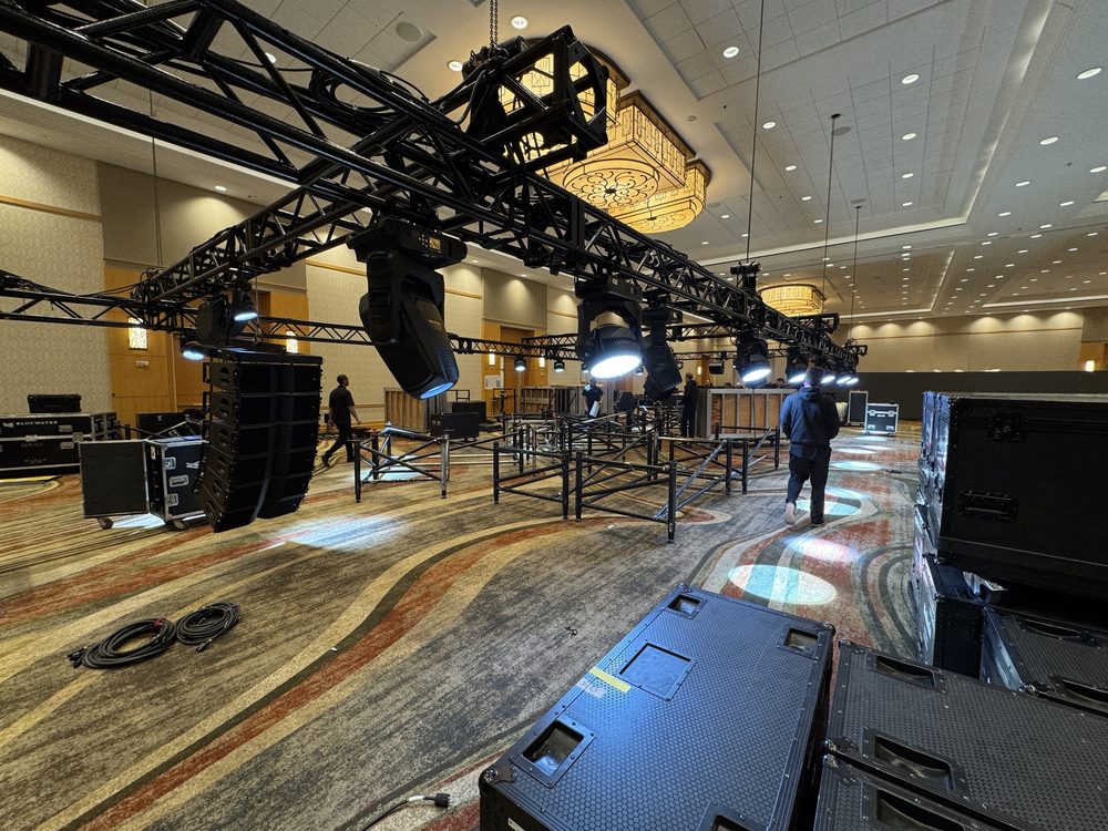 Line array speakers and moving-head lights flown from truss during a ballroom load-in