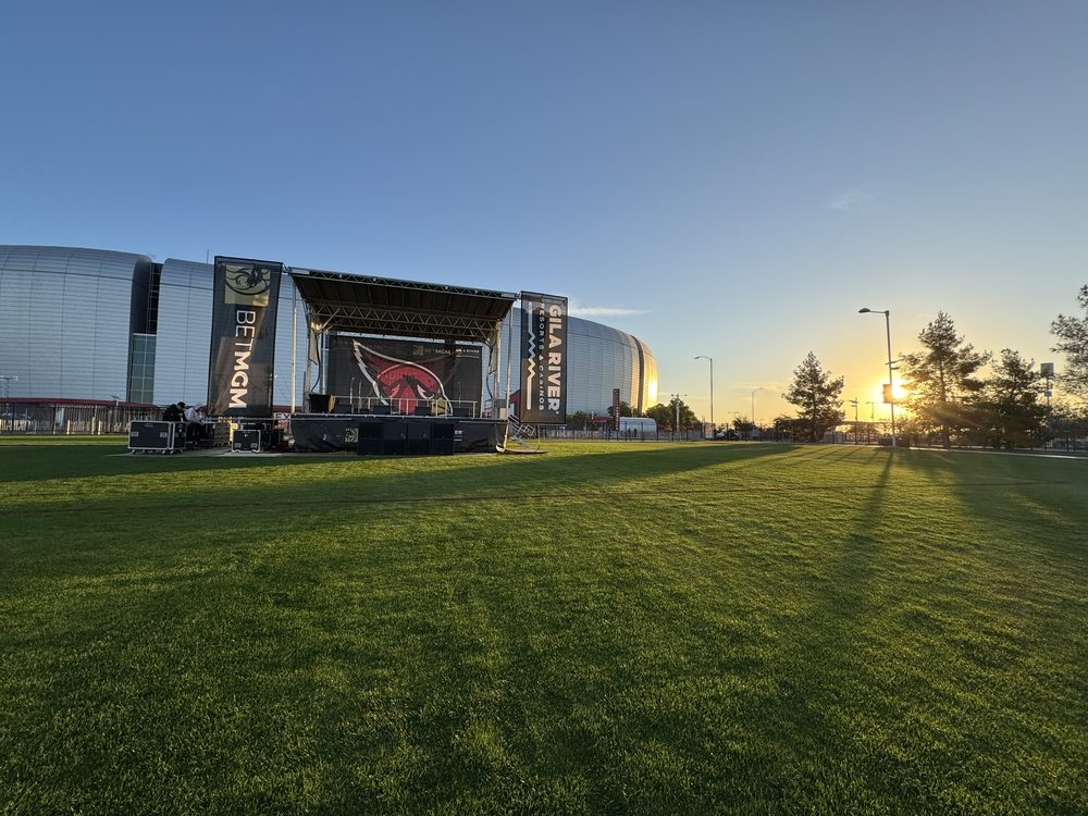 Outdoor concert stage with LED video wall set up at State Farm Stadium at sunset