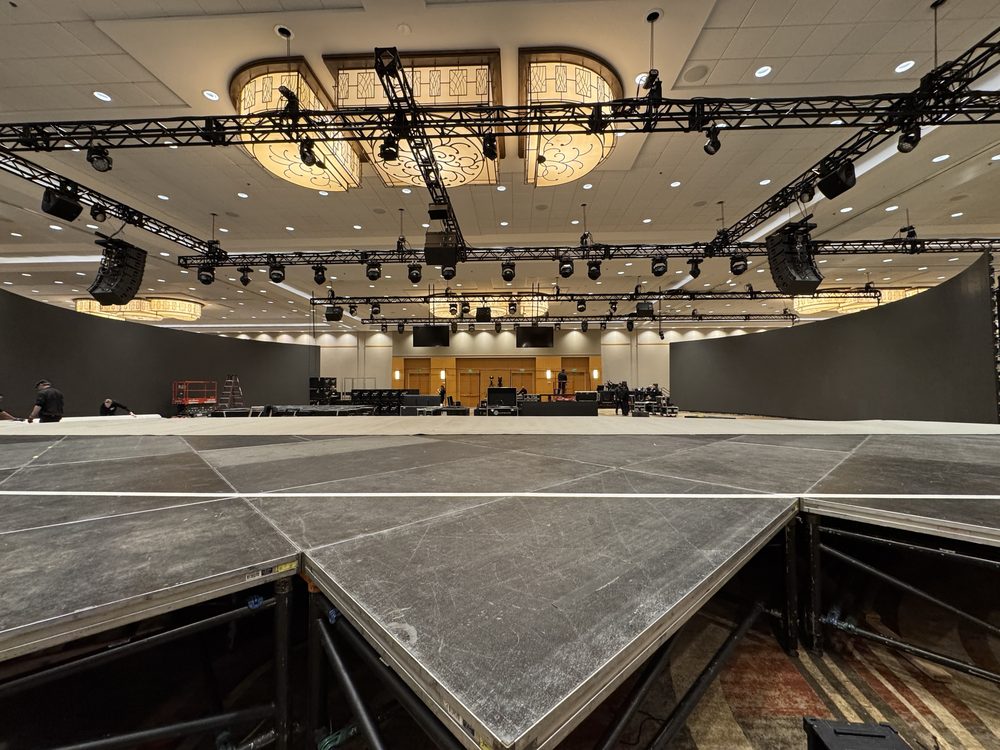 Ballroom with a large overhead truss rig, line array speakers, and moving lights during load-in